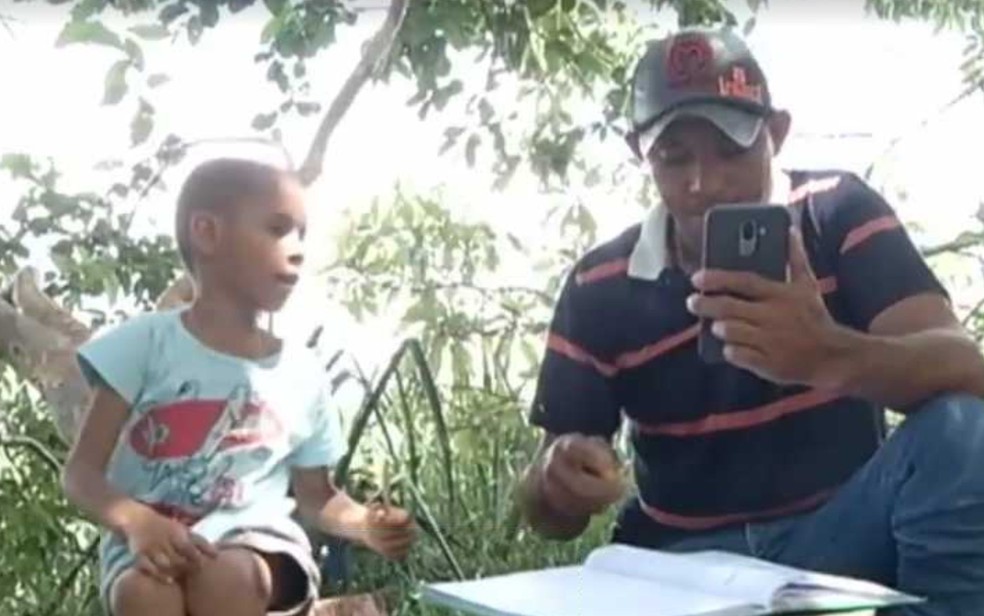 Thalys Malaquias e o pai Rony Santana Melo em cima do morro pegando sinal de internet para continuar estudos em tempo de isolamento por causa do coronavírus Doverlândia Goiás — Foto: Reprodução/TV Anhanguera