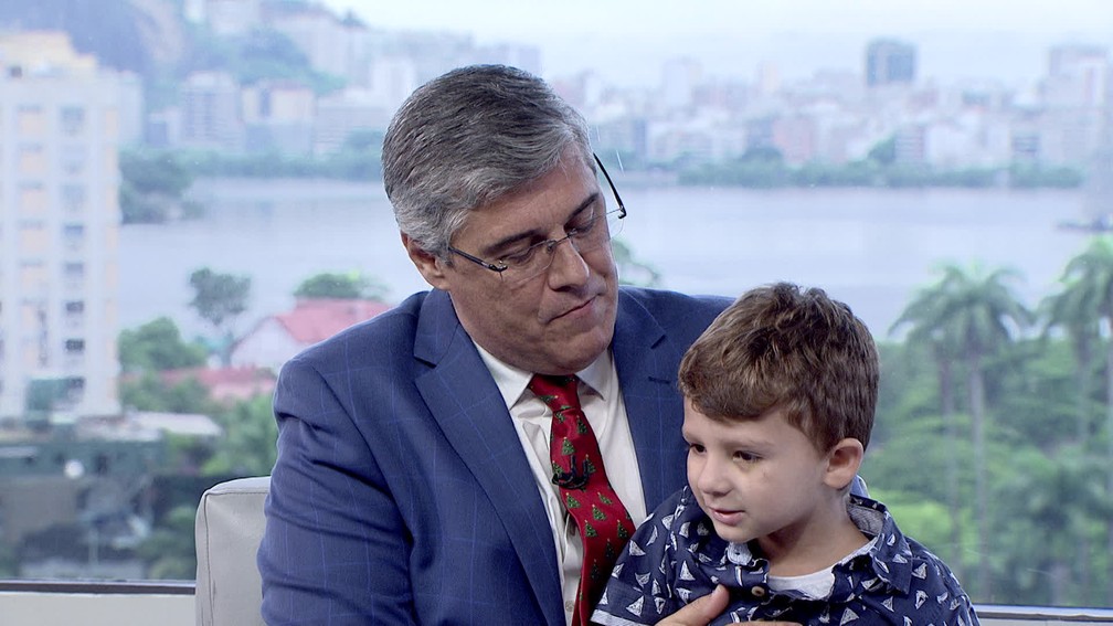 João Paulo senta no colo de Flávio Fachel durante o Bom Dia Rio — Foto: Reprodução/TV Globo