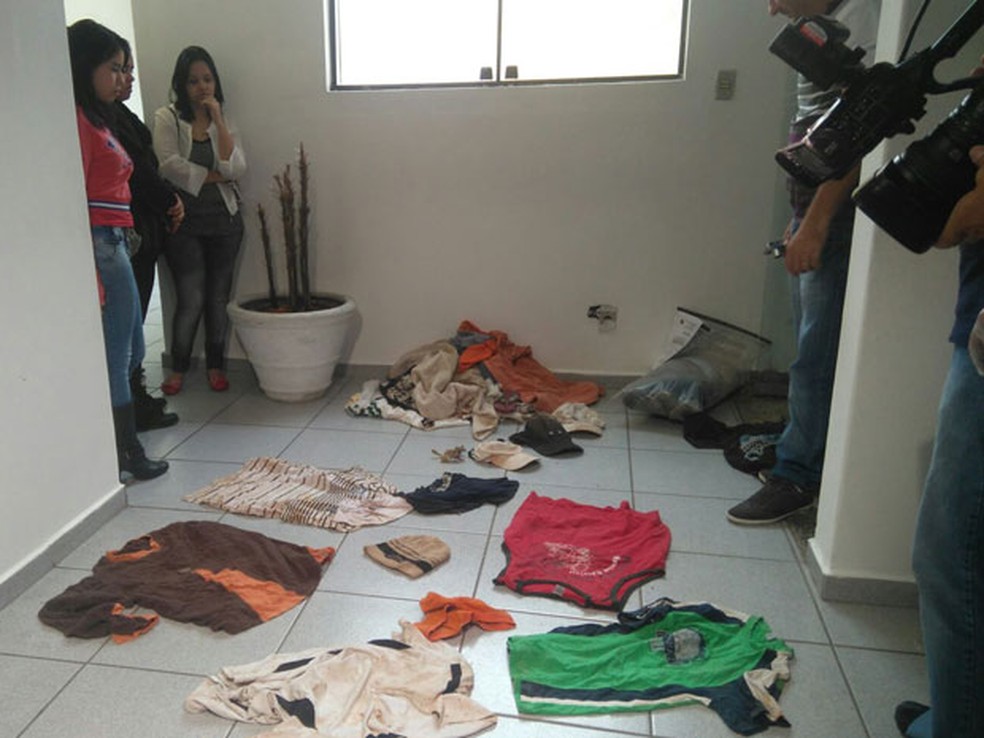 Amigas de uma das vítimas observam roupas encontradas na casa do pintor Jorge Luiz Morais de Oliveira em 2015 — Foto: Carolina Dantas/G1