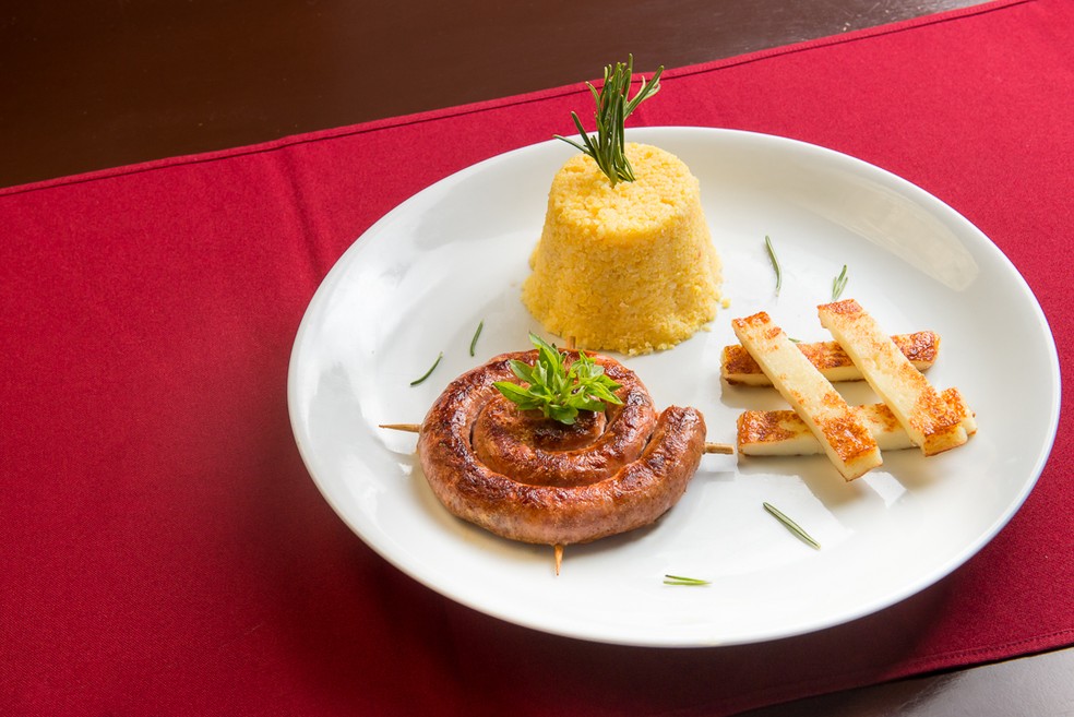 Um dos pratos é “Bem enroladinho”, composto por linguiça artesanal, grelhada na manteiga de garrafa, servida com cuscuz amanteigado e queijo coalho defumado (Foto: Kamilo Marinho)