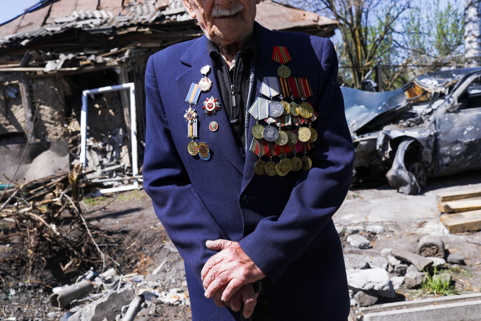 O veterano da Segunda Guerra Mundial, Ivan Lisun, 97 anos, usa uma jaqueta com suas medalhas e alfinetes fora de sua casa, que foi destruída após um bombardeio russo, em Zolochiv, perto de Kharkiv — Foto: Ricardo Moraes/Reuters