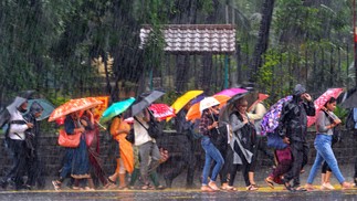 Passageiros percorrem uma rua em meio a fortes chuvas em Mumbai, Índia  — Foto: INDRANIL MUKHERJEE / AFP
