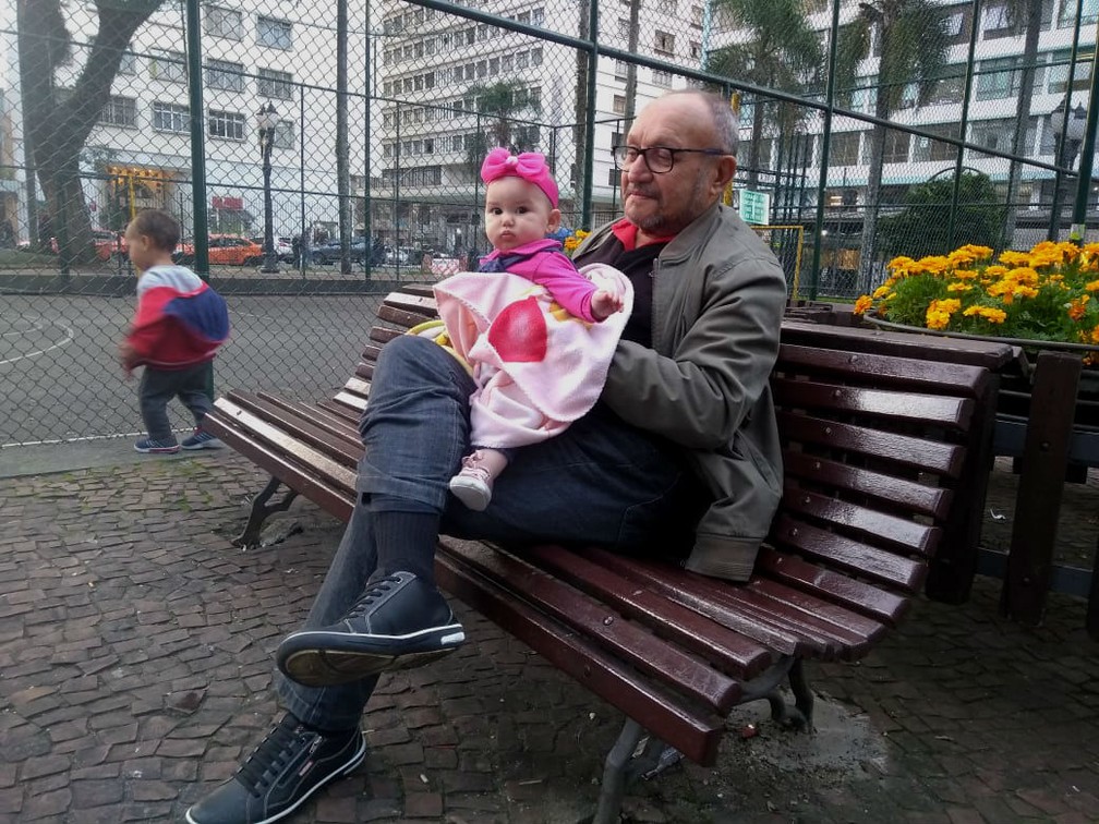 O jornalista Euclides Moraes, de 68 anos, com a neta Maria Eduarda, na Praça Osório, em Curitiba (Foto: Ederson Hising/G1 PR)