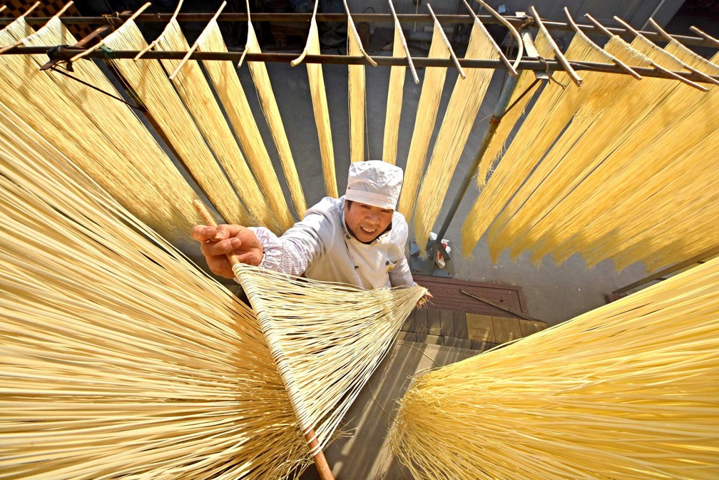 Homem pendura fios de macarrÃ£o para secar no varal de um restaurante na vila de Linyi, na provÃ­ncia de Shandong, na China (Foto: Reuters/Stringer)