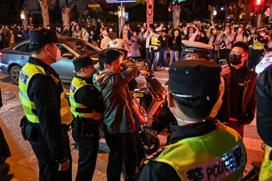Policiais confrontam um manifestante que protestava em Xangai no sábado à noite