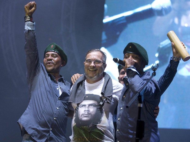 O líder máximo das Forças Revolucionárias da Colômbia, Rodrigo Londono (centro), também conhecido como Timochenko, abraça cantores do grupo Southern Rebels durante a 10ª conferência das Farc na Planície do Yari, sul da Colômbia, na noite de domingo (18) (Foto: Ricardo Mazalan/AP)