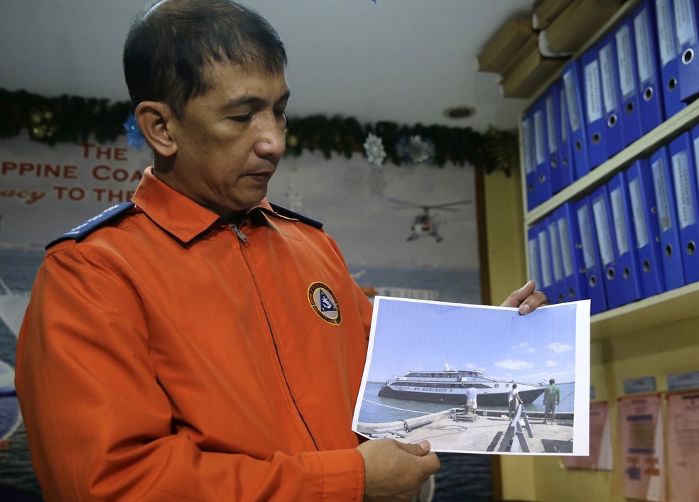 O porta-voz da Guarda Costeira, Armand Balilo, mostra uma foto de arquivo da embarcação que naufragou com 251 passageiros a bordo, nas Filipinas (Foto: AP Photo / Aaron Favila)