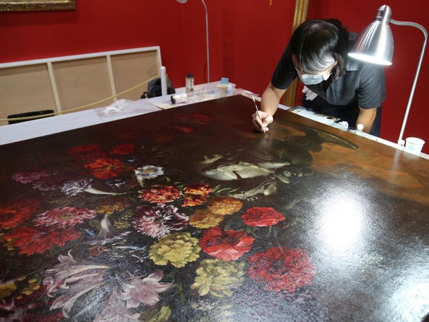 Restaurador trabalha em 'Flores', do mestre italiano do século 17 Paolo Porpora; tela já voltou à exibição em museu de Taiwan após ser danificado sem querer por garoto de 12 anos (Foto: Divulgação)