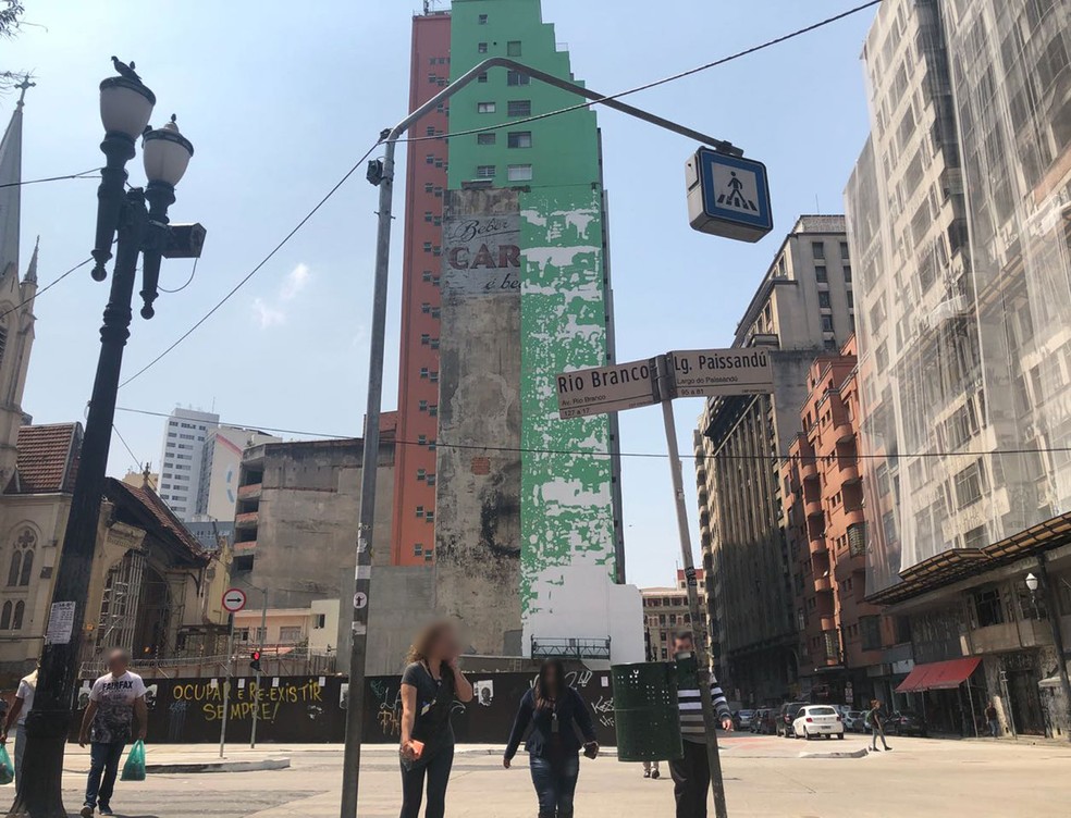 Pedestres passam em frente ao restou do Edifício Wilton Paes de Almeida; ao fundo, pintura verde cobre anúncio da Caracu no prédio vizinho — Foto: Kleber Tomaz/G1