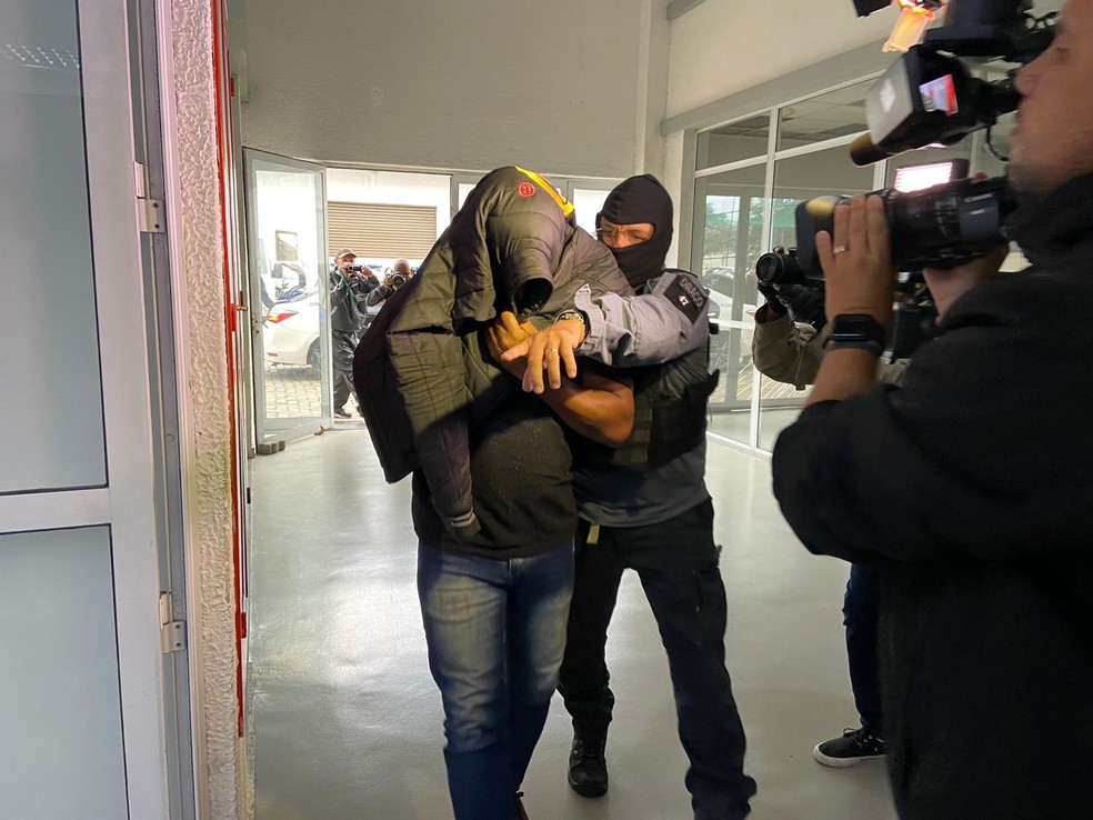 Um dos presos na Operação Heron chega à Cidade da Polícia — Foto: Lívia Torres/TV Globo