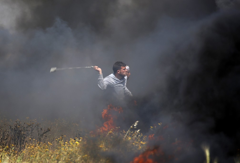 Palestino lança pedra em direção a soldados israelenses nesta sexta-feira (30) durante confronto na Faixa de Gaza (Foto: Adel Hana/AP Photo)