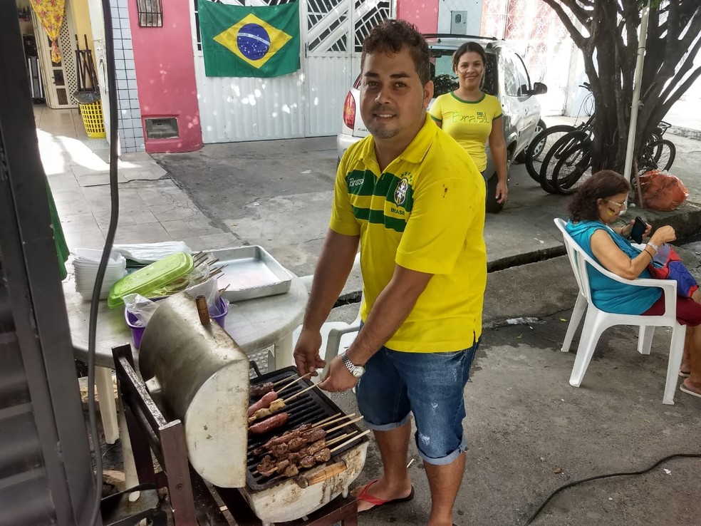 Empresário Nailton Junior prepara churrasco para os amigos, que assistem ao jogo do Brasil na Copa pela TV, instalda sob uma tenda no meio da rua na Ponta Grossa, Maceió (Foto: Derek Gustavo/G1)