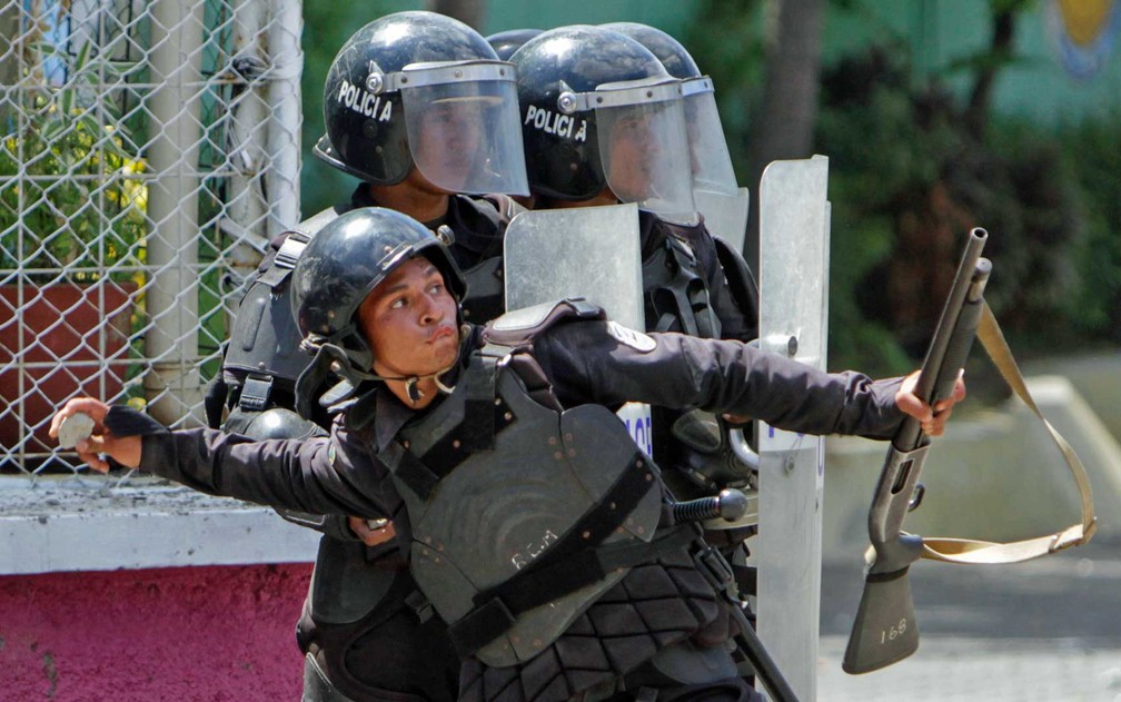 Policial joga uma pedra contra manifestantes (Foto: Inti Ocon / AFP Photo)