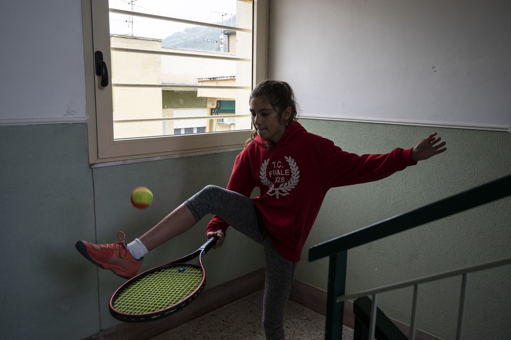 Carola Pessina pratica tênis na escada antes de jogar com uma amiga no telhado de sua casa em Finale Ligure, região de Liguria, no noroeste da Itália, durante o isolamento do país para impedir a propagação da COVID-19  — Foto:  Marco Bertorello/AFP