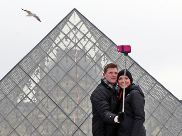 Casal tira foto com o 'pau de selfie' em frente ao museu do Louvre, em Paris (Foto: Remy de la Mauviniere/AP)