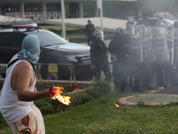 Manifestantes atira um coquetel molotov em direção a policiais durante protesto contra a PEC 55, que limita os gastos públicos para os próximos 20 anos, na Esplanada dos Ministérios, em Brasília (Foto: Eraldo Peres/AP)