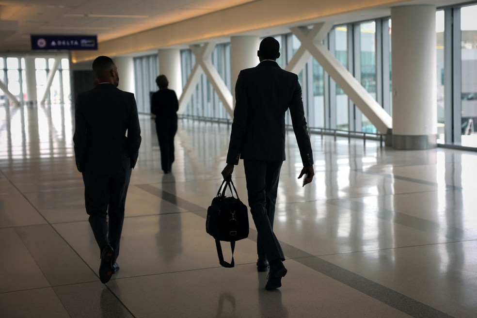 Três pessoas andam em setor do aeroporto de Nova York — Foto: Mike Blake/REUTERS