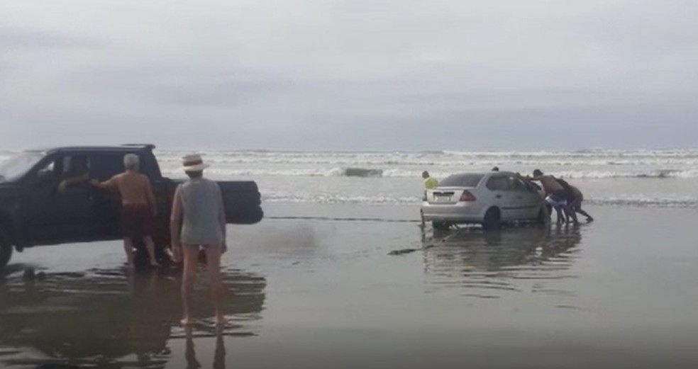 Moradores das regiões próximas à praia de Itanhaém formaram uma ‘corrente de solidariedade’ para desatolar veículo — Foto: Reprodução