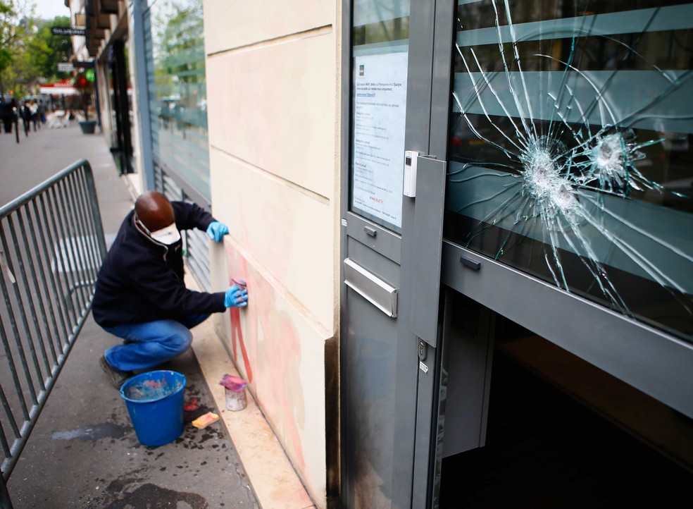 Homem apaga pixação na sede da campanha da candidata de extrema-direita à presidência francesa, Marine Le Pen, em Paris, nesta quinta-feira (13)  (Foto: Francois Mori/ AP)
