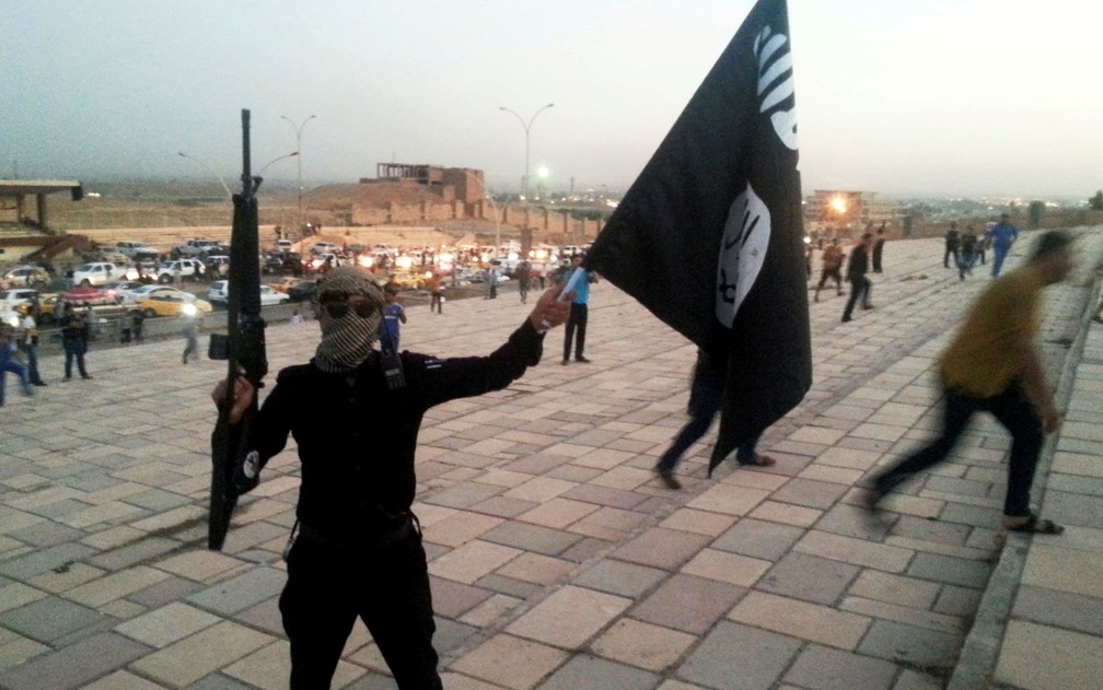 Combatente do Estado Islâmico exibe arma e bandeira do grupo em rua de Mossul, no Iraque, em foto de 23 de junho de 2014 (Foto: Reuters/Stringer)