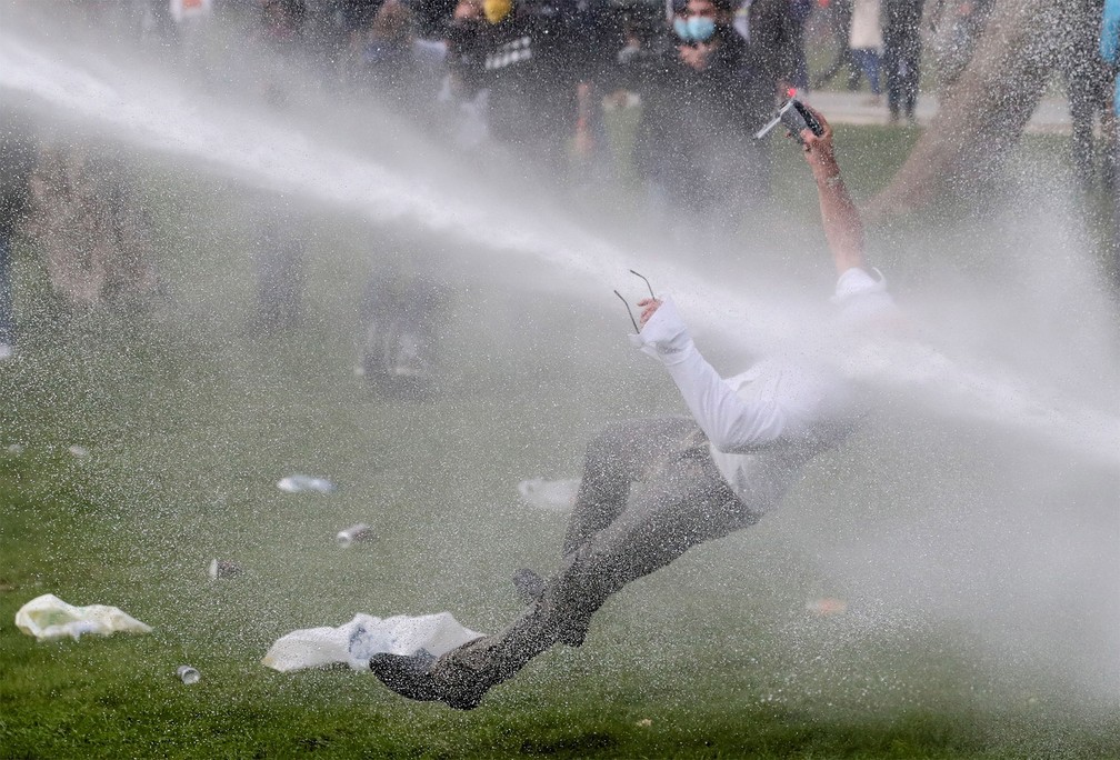 1º de maio - Homem é derrubado por canhão de água da polícia em confronto durante protesto contrário às medidas de prevenção do coronavírus realizado em um parque de Bruxelas, na Bélgica — Foto: Yves Herman/Reuters