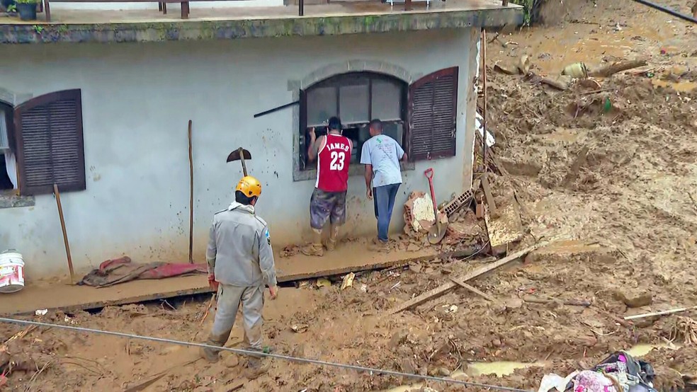 Socorristas buscam vítimas na janela do segundo andar de um prédio — o primeiro foi soterrado — Foto: Reprodução/TV Globo