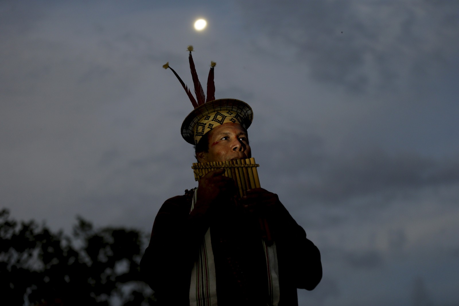 O líder espiritual Moisés Pyãko toca sua flauta feita com madeira da floresta após  cerimônia da caiçuma — Foto: Domingos Peixoto / Agência O Globo