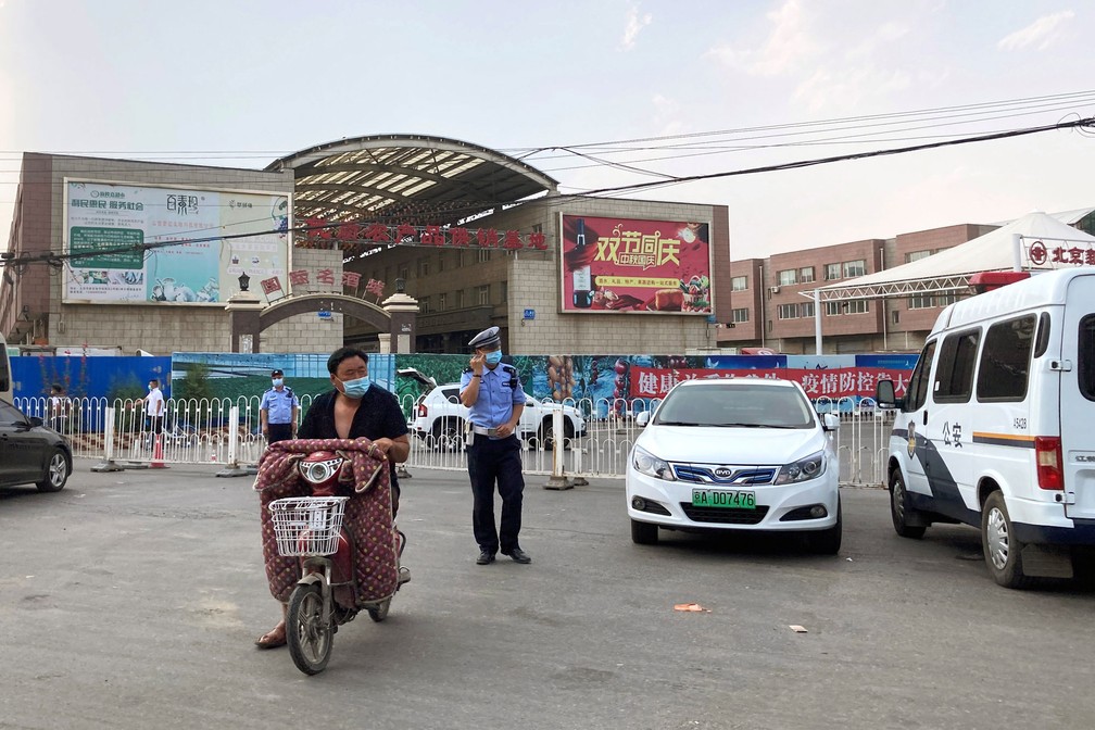 Policiais com máscaras são vistos do lado de fora do mercado atacadista de Xinfadi, que foi fechado para negócios após a detecção de novas infecções pelo novo coronavírus, em Pequim, China, neste sábado (13)  — Foto: Martin Pollard/ Reuters