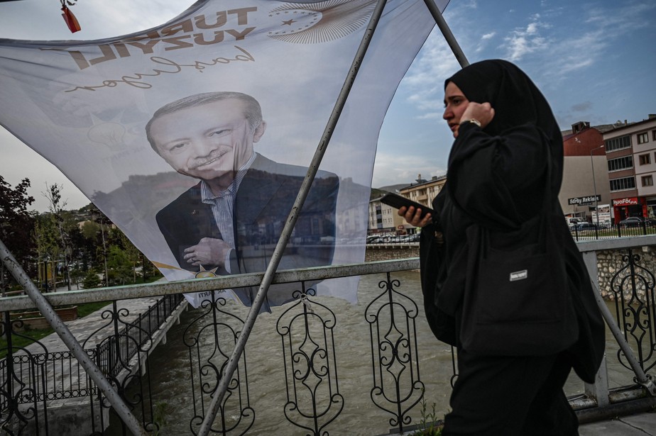 Turca passa em frente de bandeira com o rosto de Erdogan no nordeste do país; valorização da liberdade religiosa.
