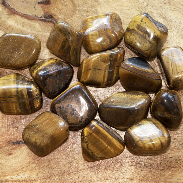 Top view of tiger eye gemstones on a wooden surface (Foto: Getty Images/iStockphoto)