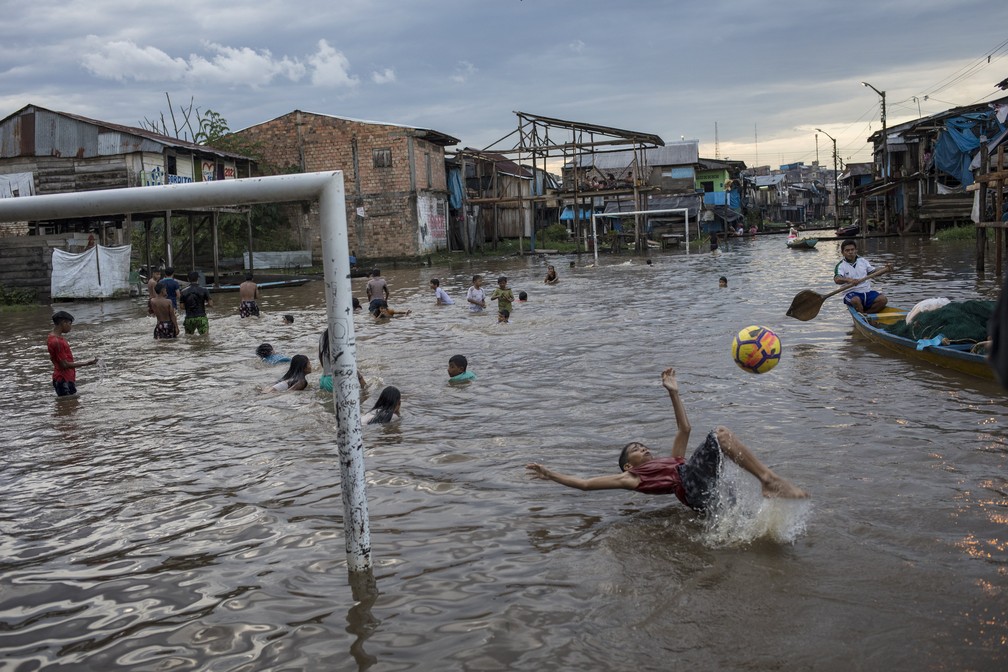 20 de março - Um menino chuta uma bola em uma área alagada da comunidade de Belen, em Iquitos, Peru — Foto: Rodrigo Abd/AP