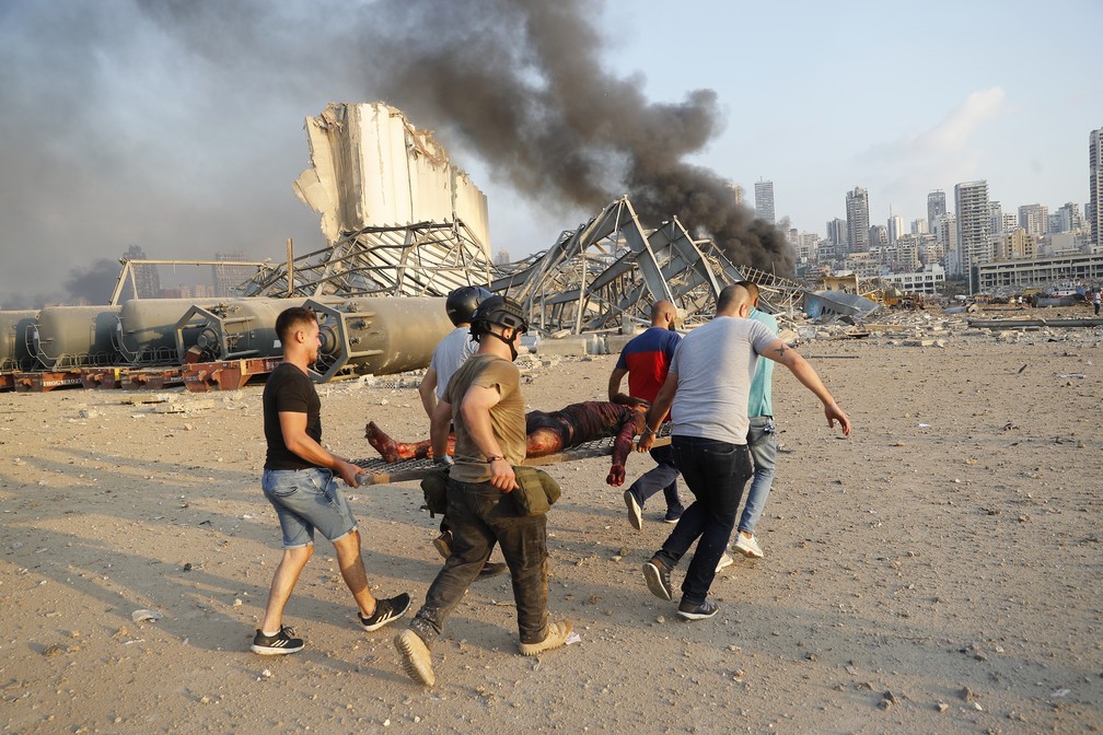 Homens carregam ferido da explosão em Beirute — Foto: Hussein Malla/AP