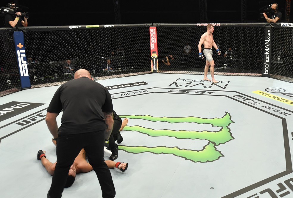 Davey Grant festeja a vitória enquanto Martin Day fica caído no octógono do UFC 251 — Foto: Getty Images