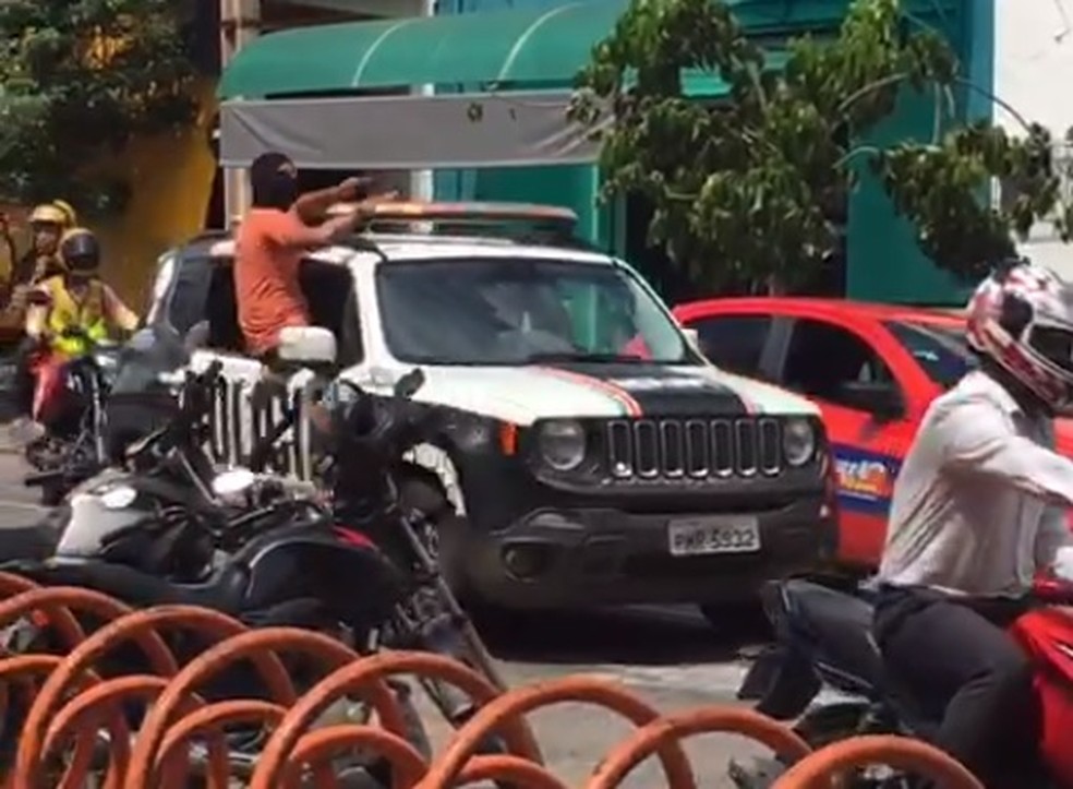Homem encapuzado em carro da polícia manda comerciantes baixarem as portas em Sobral — Foto: Reprodução