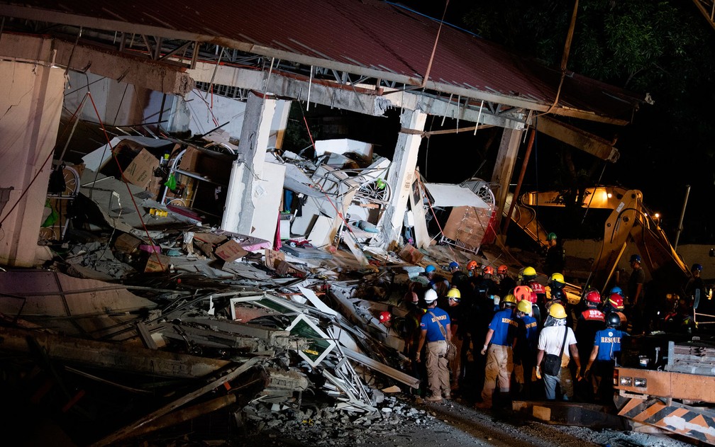 Resgatistas tentam retirar pessoas de prédio que desabou sob supermercado em Porac, Pampanga, nas Filipinas, após terremoto, na segunda-feira (22) — Foto: Noel Celis/AFP