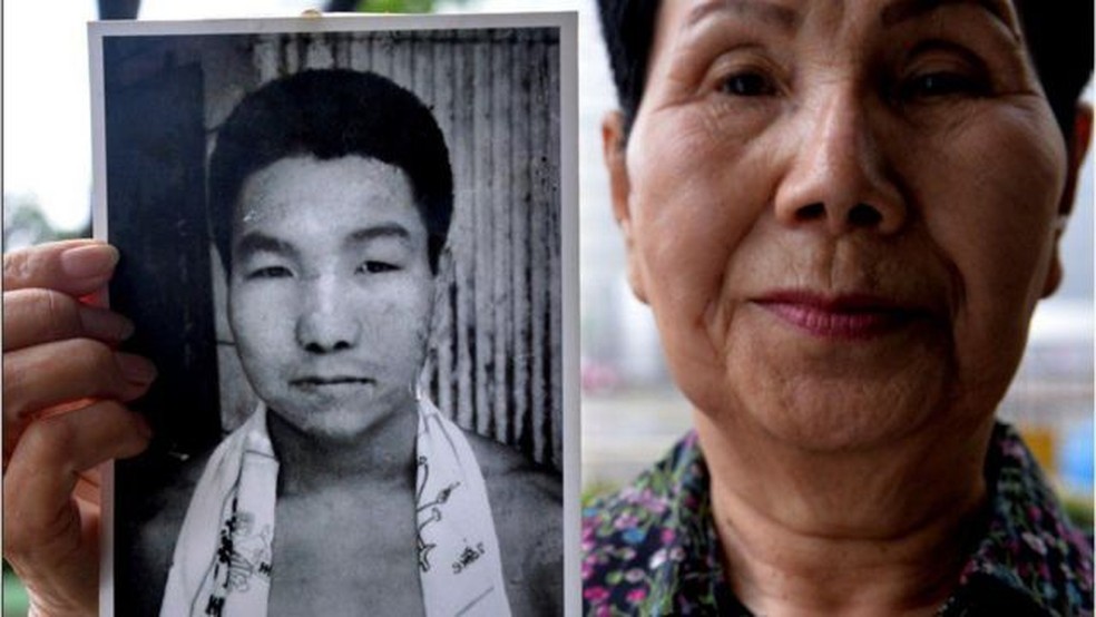 Mulher mostra foto do homem jovem — Foto: AFP