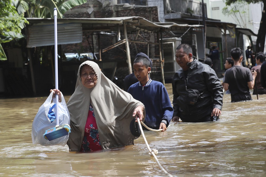 Moradores em um bairro inundado em Tanggerang, nos arredores de Jacarta, na Indonésia — Foto: Tatan Syuflana/AP