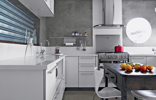 A cozinha foi revestida de Tecnocimento e tem móveis brancos, que ajudam a clarear o ambiente. Projeto da arquiteta Claudia Haguiara