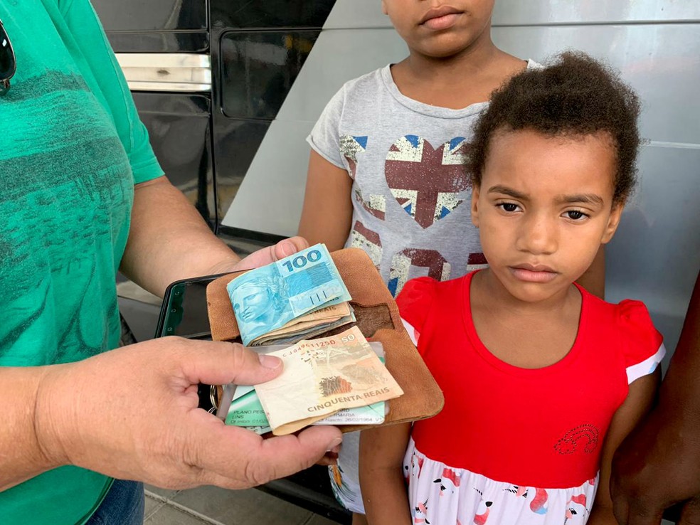 Ao lado de alguns dos filhos da mulher que achou sua carteira, Liliane Nakamura recebe tudo o que havia perdido na rua — Foto: J. Serafim/Divulgação