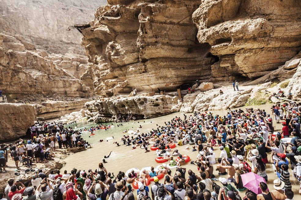 Centenas de pessoas acompanham a disputa em Wadi Shab, Omã, em imagem de 2016 — Foto: Balazs Gardi/Red Bull/AFP