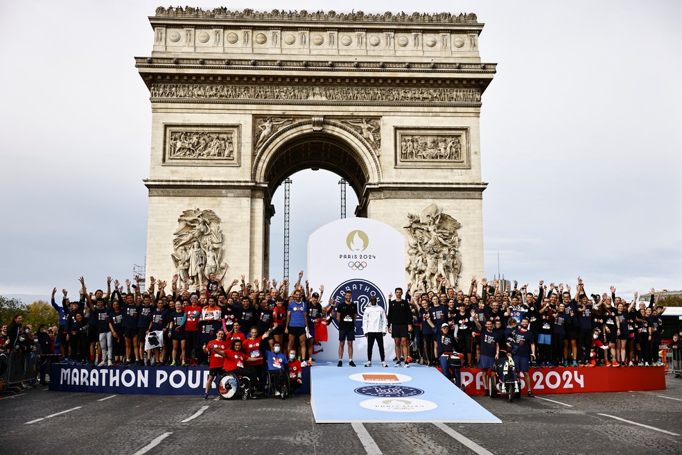 O atleta queniano Eliud Kipchoge aplaude corredores no pódio da "Maratona para Todos" no Arco do Triunfo, em Paris — Foto: REUTERS/Sarah Meyssonnier