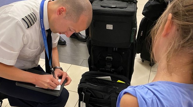 A pequena Lena observa enquanto o piloto Josh Duchow, da United Airlines, escreve um bilhete para a Fada do Dente (Foto: Acervo Pessoal)