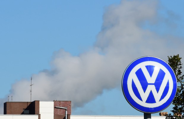 Logo da montadora alemã Volkswagen é visto em fábrica na Alemanha, com fumaça ao fundo (Foto: Getty Images/Arquivo)