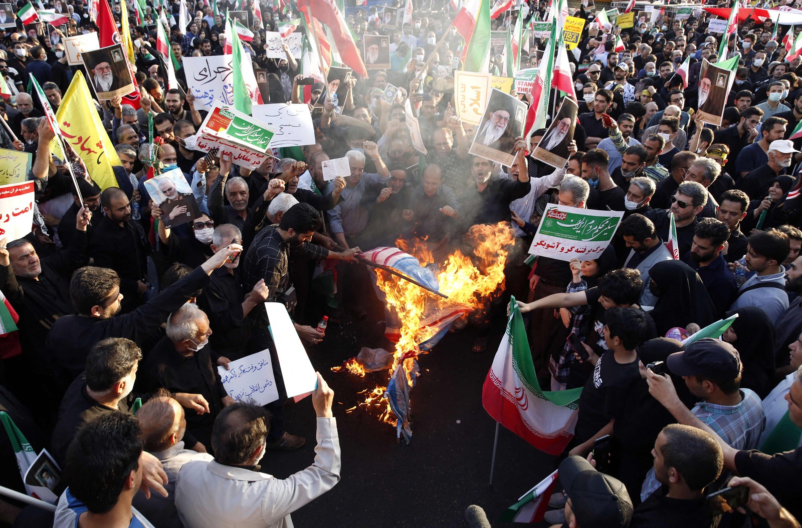 Manifestantes iranianos pró-governo queimam bandeiras dos EUA, Israel e Grã-Bretanha durante um ato contra os recentes protestos anti-governo no Irã, em Teerã — Foto: AFP
