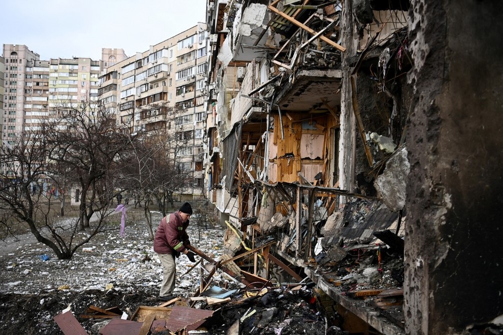 Guerra na Ucrânia: Homem limpa destroços em prédio residencial atingido por bombardeio russo — Foto: Daniel LEAL / AFP