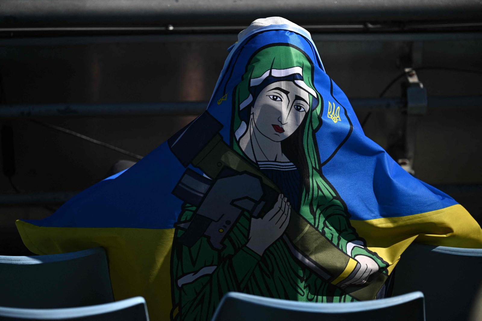 Espectador vestindo uma bandeira ucraniana com uma figura santa segurando equipamento militar senta-se nas arquibancadas no quinto dia do torneio Aberto de Tênis da Austrália, em Melbourne — Foto: ANTHONY WALLACE / AFP