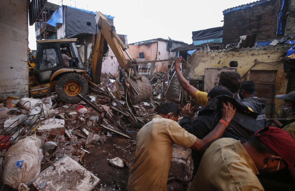Equipes de resgate limpam os escombros em busca de desaparecidos após prédio de 3 andares desabar em meio às fortes chuvas de monções em Mumbai, na Índia, em 10 de junho de 2021 — Foto: Rafiq Maqbool/AP
