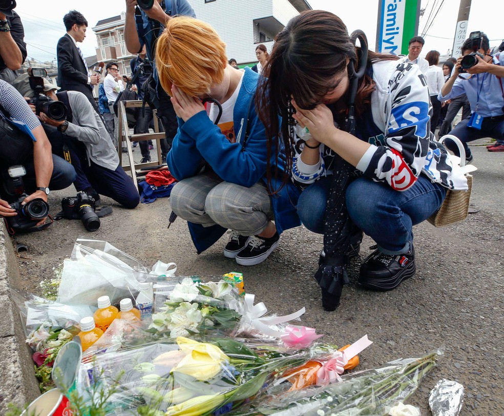 Mulheres rezam apÃ³s deixarem flores perto do ponto de Ã´nibus onde crianÃ§as foram esfaqueadas em Kawasaki, no JapÃ£o  â€” Foto: Kyodo News via AP