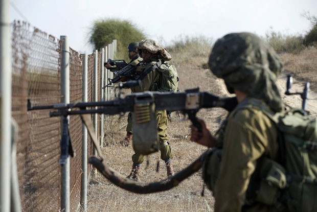 Soldados israelenses se posicionam ao lado de cerca na cidade de Sderot durante infiltração de militantes palestinos nesta segunda-feira (21) (Foto: Baz Ratner/Reuters)