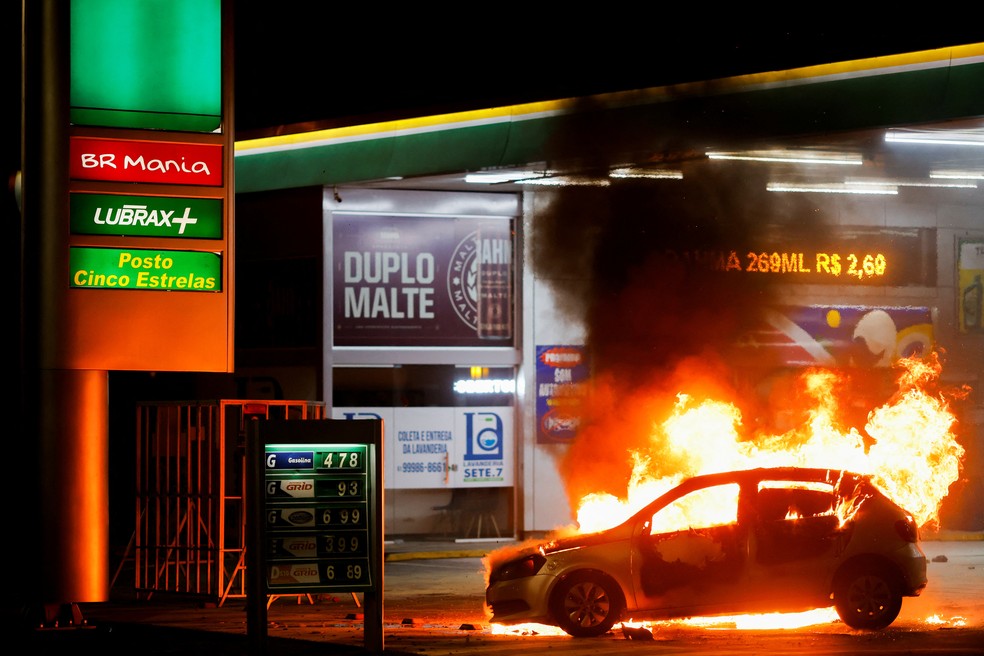 Carro é incendiado em frente à posto de gasolina na noite desta segunda-feira (12), em Brasília. — Foto: Adriano Machado/Reuters